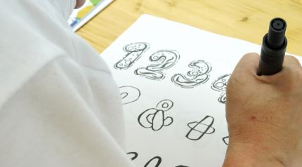 複数名の障がい者アーティストによって、選ばれたフォント形状に模様を描いていく。